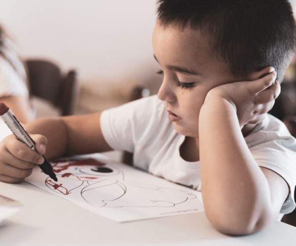 Young child focused on coloring a picture in a classroom environment.